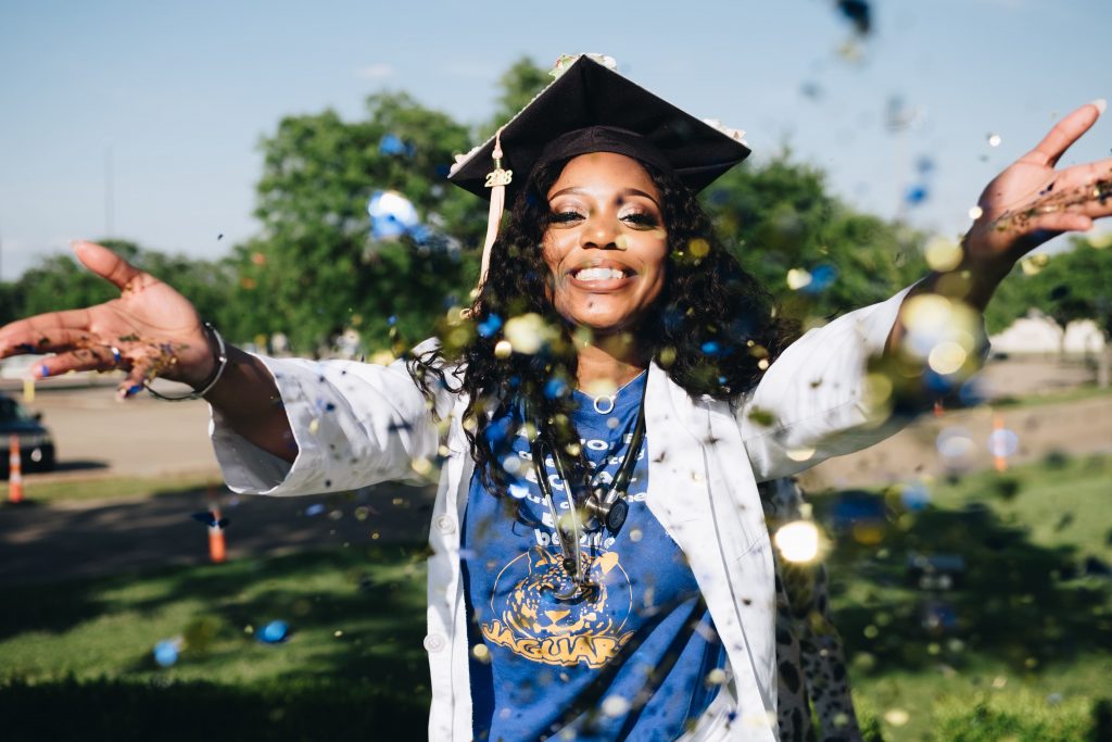 A student in academic regalia celebrates graduation