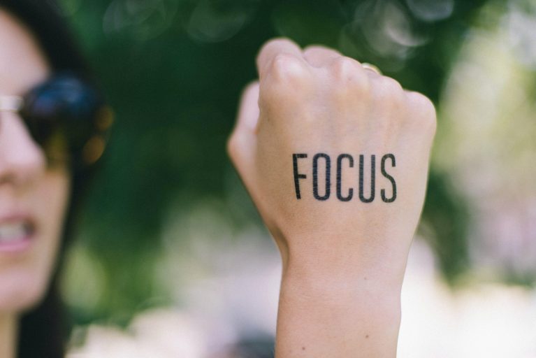 A woman with the word Focus tattooed on her right hand