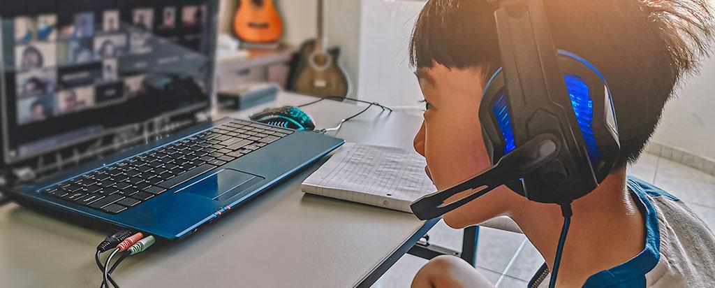 A boy in headphones during a remote learning class