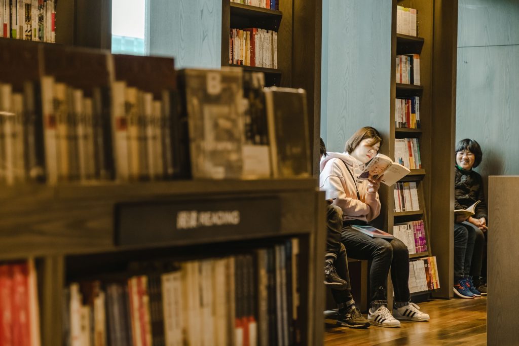 A student reading a book near the window in a library